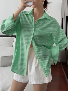 Detail of green striped long-sleeve loose shirt with front button and chest pocket