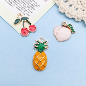 Detailed close-up of cherry, peach, and pineapple alloy charms on light blue background