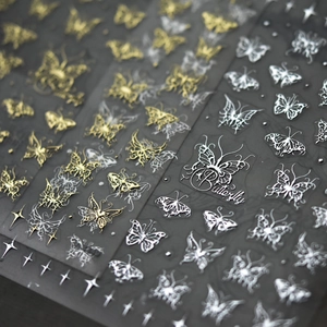 Macro shot of 5D gold and silver butterfly nail stickers with cross star patterns