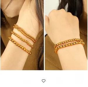 Detailed macro view of polished gold metal bead bracelets on woman's wrist