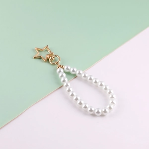 Detail of white glass pearl bead keychain featuring a gold star-shaped metal clasp