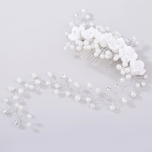 Close-up of bridal hair comb with white fabric roses, pearls, and rhinestone hair vine