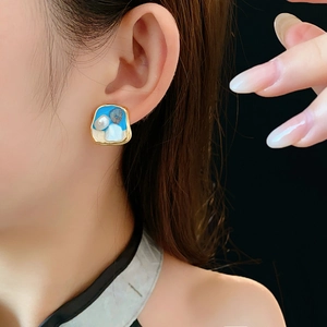 Primo piano di orecchini vintage in smalto blu e perle indossati da una modella