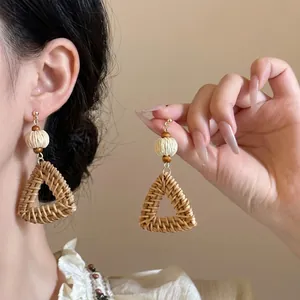 Bohemian woven raffia triangle earrings with wooden beads on a clean neutral background