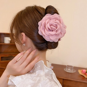 Detailed view of an elegant pink fabric floral hair claw clip on a low bun hairstyle