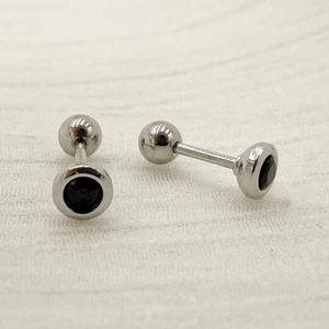 Macro shot of silver titanium steel barbell earrings with black round zircon and screw back