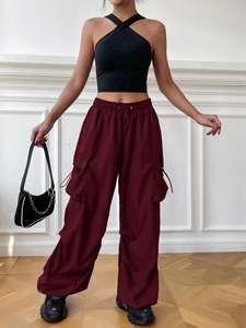 Detail of dark burgundy wide-leg cargo pants featuring large side pockets and drawstring waist