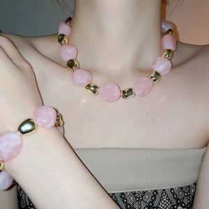 Detail of pink acrylic beaded necklace and bracelet set worn by a model in soft light