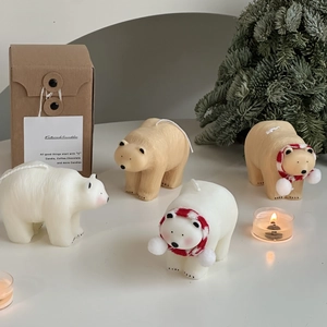 Detail of white polar bear candles with red scarves near a festive pine gift box