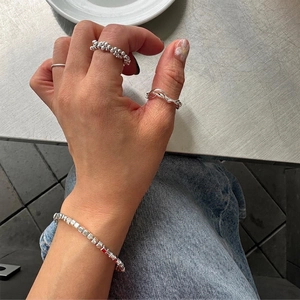 Set of minimalist 925 sterling silver rings and beaded bracelet on a casual denim style