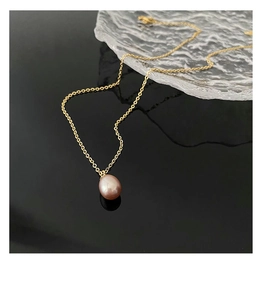 Detailed close-up of a pink-purple pearl pendant on a gold titanium steel chain necklace