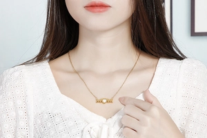 Macro shot of gold MOM pendant with heart opal detail on model's neckline