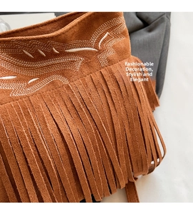 Detail of brown suede bucket bag with white embroidery and bohemian long fringe decoration