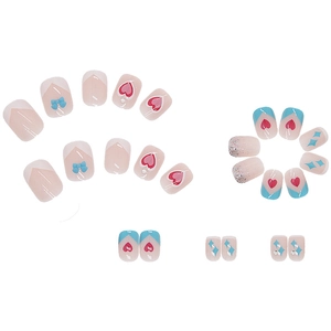 Pink and blue press-on nails set with heart and bow designs on a white background