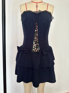 Détail de la robe à fines rayures avec dentelle noire et nœuds décoratifs sur le côté