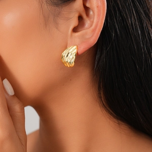 Gros plan d'une boucle d'oreille dorée géométrique avec motif de coquillage