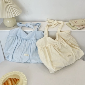 Detail of ruched canvas tote bags with adjustable bow straps in blue and cream colors