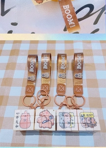 Detail of Capybara mini cube keychains with brown ribbons on checkered fabric background