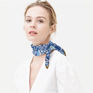 Detail of a blue floral silk scarf worn by a model for elegant neck decoration