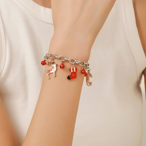 Detailed view of Christmas charm bracelet with red bells and snowflake pendants on wrist