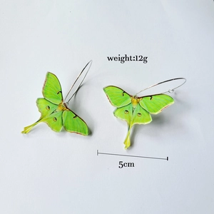 Detail view of green acrylic moth earrings showing 5cm width and 12g weight specifications