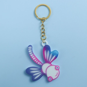 Gros plan d'un porte-clés libellule avec dégradé violet-bleu et anneau en métal doré