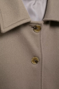Close-up of wool coat lapel with grey fabric texture and tortoise pattern resin buttons