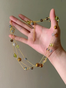 Detail of multi-layer beaded necklace with gold chain and colorful glass stones