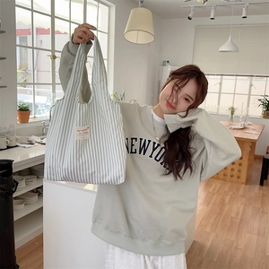 Detail of green striped canvas tote bag with woven label on a casual casual lifestyle background
