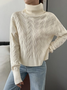 Close-up of knit texture on women's off-white turtleneck sweater with ribbed cuffs