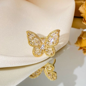 Adjustable golden butterfly ring with sparkling crystals on silk fabric background