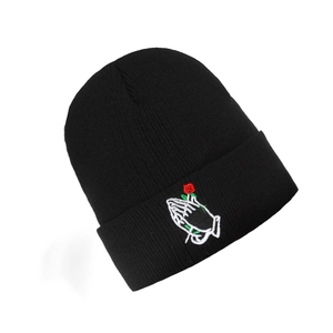 Detail of embroidered praying hands with red rose on black knitted beanie hat