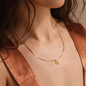 Detail of minimalist gold-plated box chain necklace with a polished hollow circle pendant