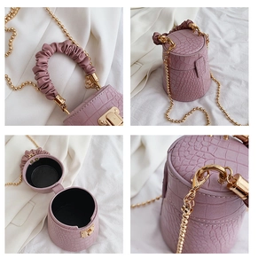 Detail view showing purple crocodile texture, ruched handle, and gold chain of the bucket bag