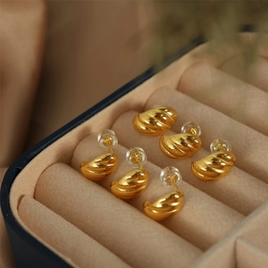 Three pairs of polished gold twisted horn C-shape stud earrings in a jewelry box