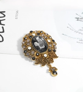 Close-up of vintage gold brooch with grey gemstone and crystal floral details