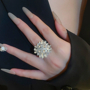 Close-up of a sparkling flower-shaped ring with crystal clusters worn on a finger