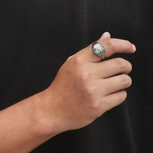 Punk style snake ring in vintage silver with green crystal eyes on a textured background