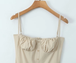 Nahaufnahme von beigem Trägerkleid mit geraffter Brust und Knopfdetails