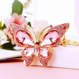 Golden butterfly keychain with pink crystals and rhinestones on a decorative gift box