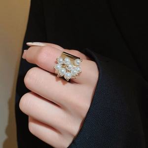 Detail of gold metal ring featuring a cluster of elegant pearls worn by a model