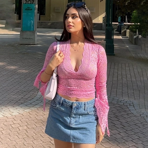 Dettaglio del top in pizzo rosa con scollo a V e maniche lunghe a campana e motivi floreali