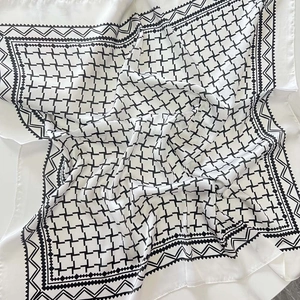 Detail of silk-like square scarf featuring black and white geometric star patterns