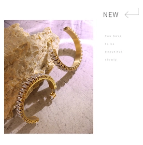 Detail of C-shaped 18K gold-plated earrings with rectangular zircon on raw stone