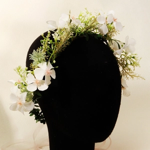 White fabric floral wreath with green leaves and ribbon adjustment on a display head