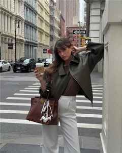 Foto street style di una giacca di pelle vintage ampia marrone scuro per strada