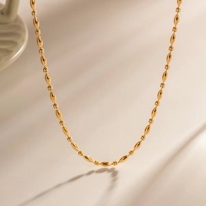 Collana in acciaio inossidabile oro 18K con perline ovali e tonde su sfondo bianco