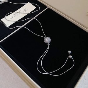 Detailed view of silver zircon sphere pendant on adjustable chain over black velvet
