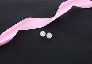Detailed view of round S925 silver stud earrings with colorful crystal texture on black