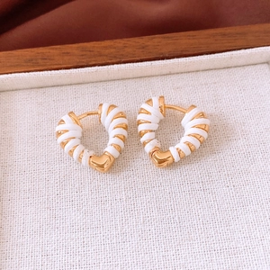 Close-up of 18k gold heart hoop earrings with white thread wrapping on textured fabric